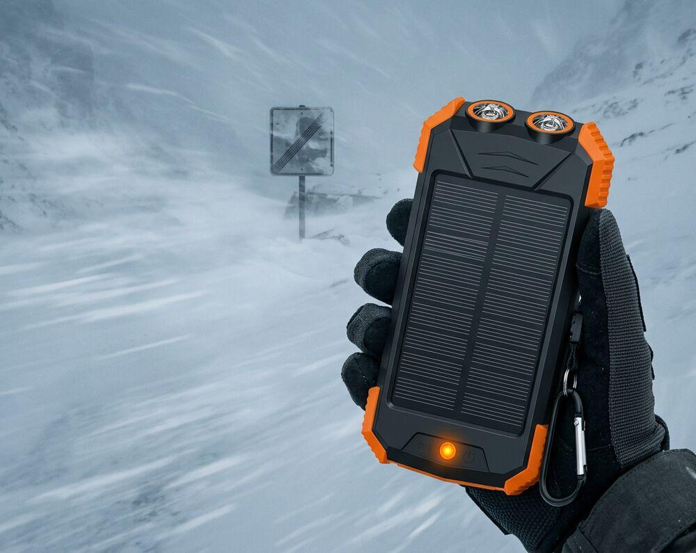 Gloved hand holding the OSTNER solar power bank in a snowstorm